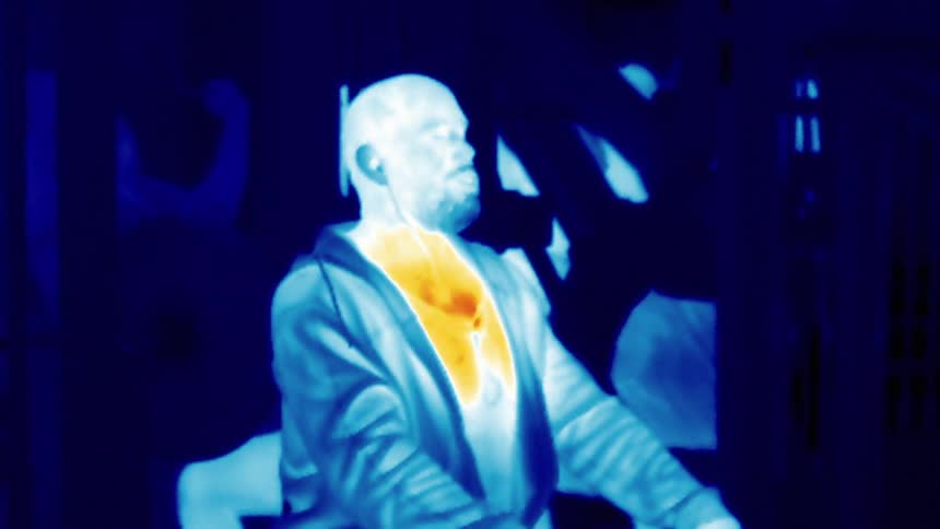 A thermal image is captured of a man sitting inside of a gym