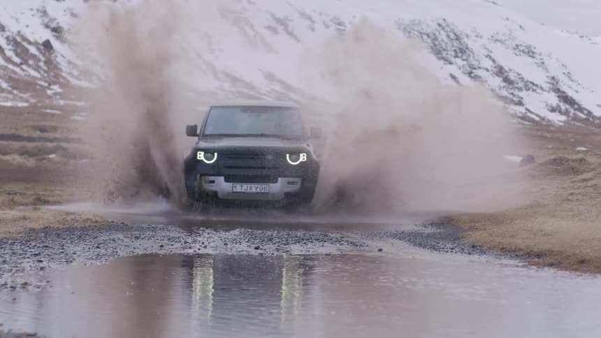 A black car passing through a puddle of water and making a splash of water