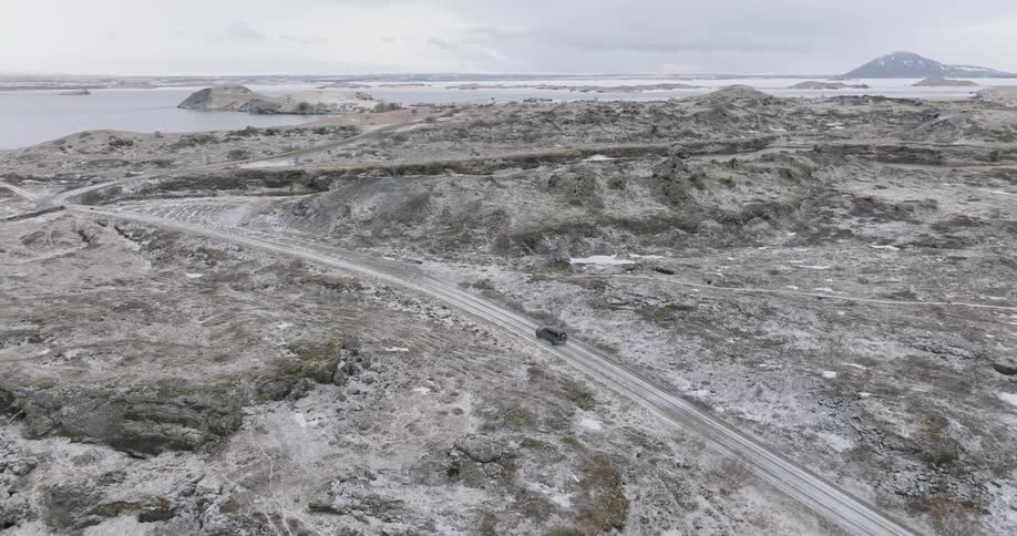 Aerial of a car driving on a road with snowy mountains in winter