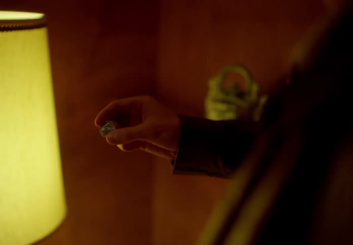 A man plays with a coin between his fingers then flips it and grabs it in the air