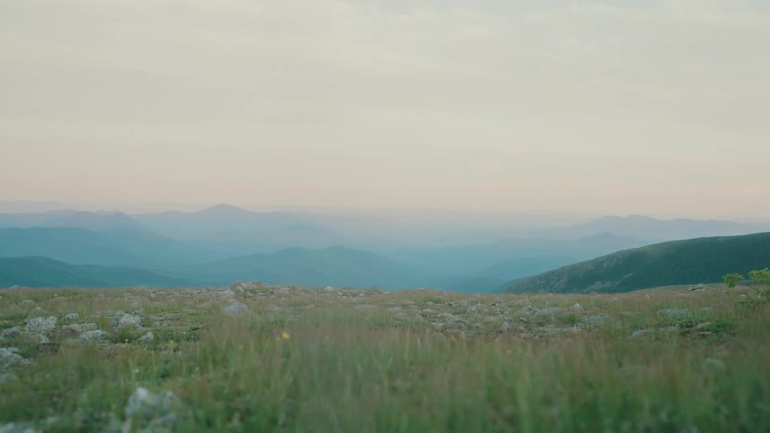 View of a grassland amidst mountains under a morning sky