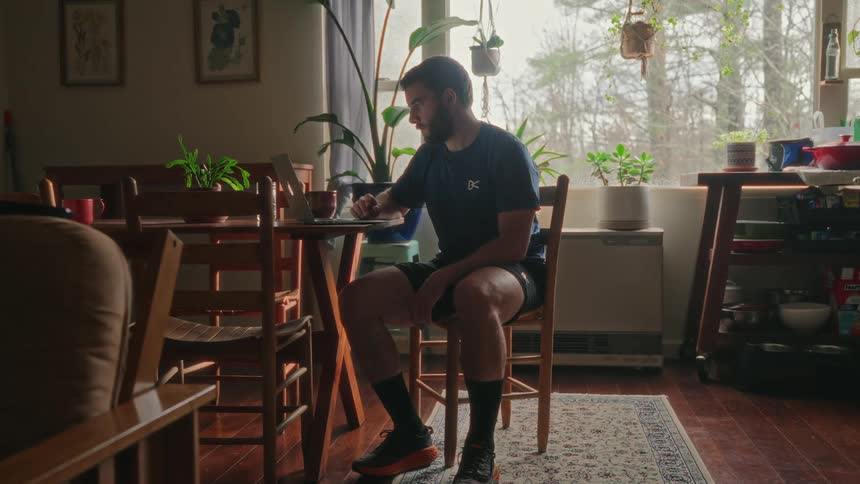 A man sitting at a living room table using a laptop