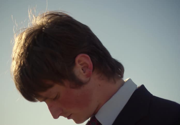 Businessman wearing glasses a black suit looks around in the field