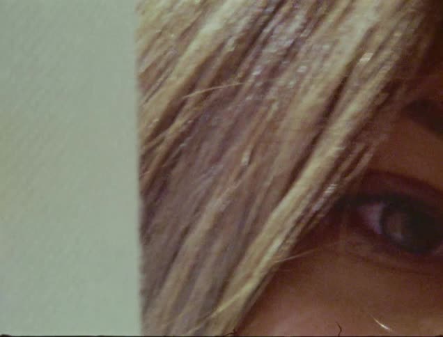A woman peaks one eye past the curtain