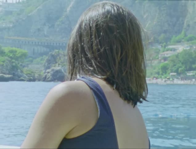 Woman running her hand through her hair while on a boat by the seaside