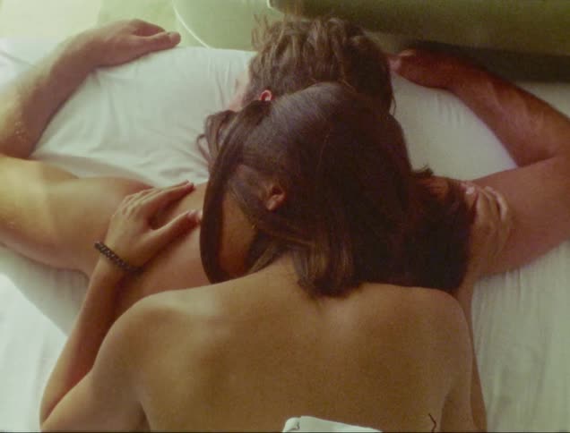 A wife resting on her husband on the bed