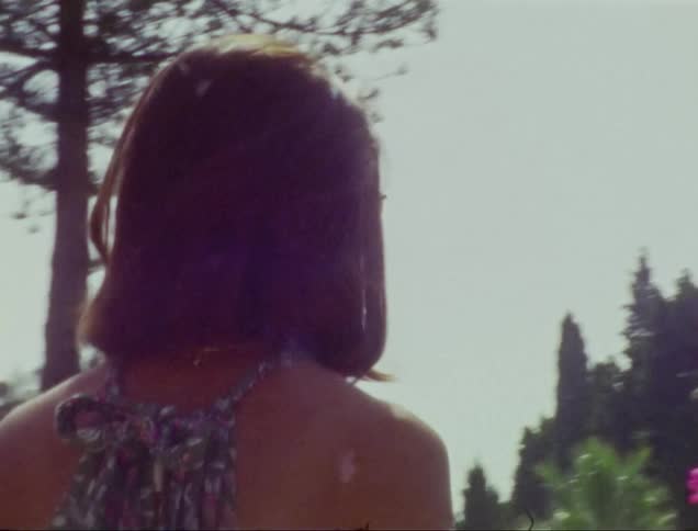 Woman with her back turned fixing her hair amidst a garden