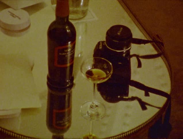 Drink in a crystal glass with a bottle and camera beside it