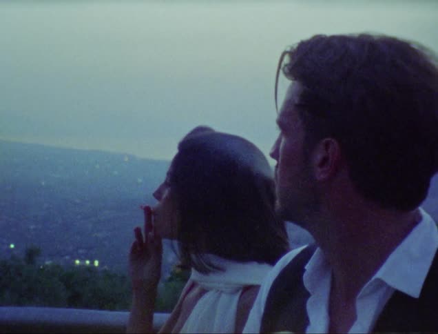 A man and a woman share a cigarette
