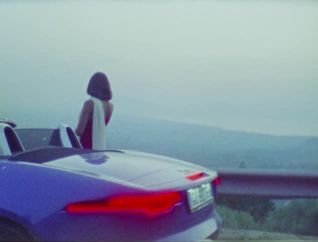 A woman standing on the road with a luxury pink car