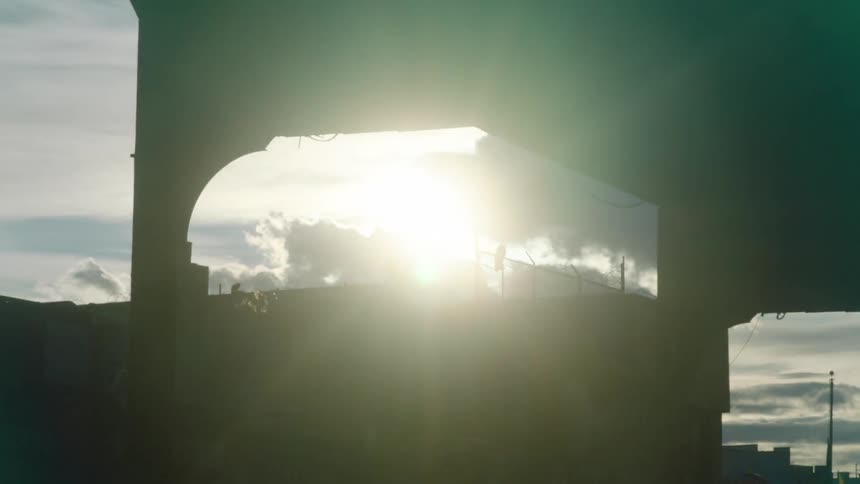 Sun shines brightly through opening in building wall on cloudy day