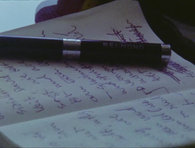 A mans hand places a pen down on a tiny open notebook