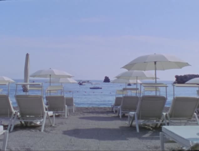 Boats move through water in line of sight of beach chairs