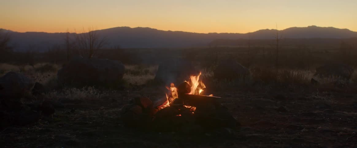 Landscape of a campfire with fire mountains on the horizon and a morning sky
