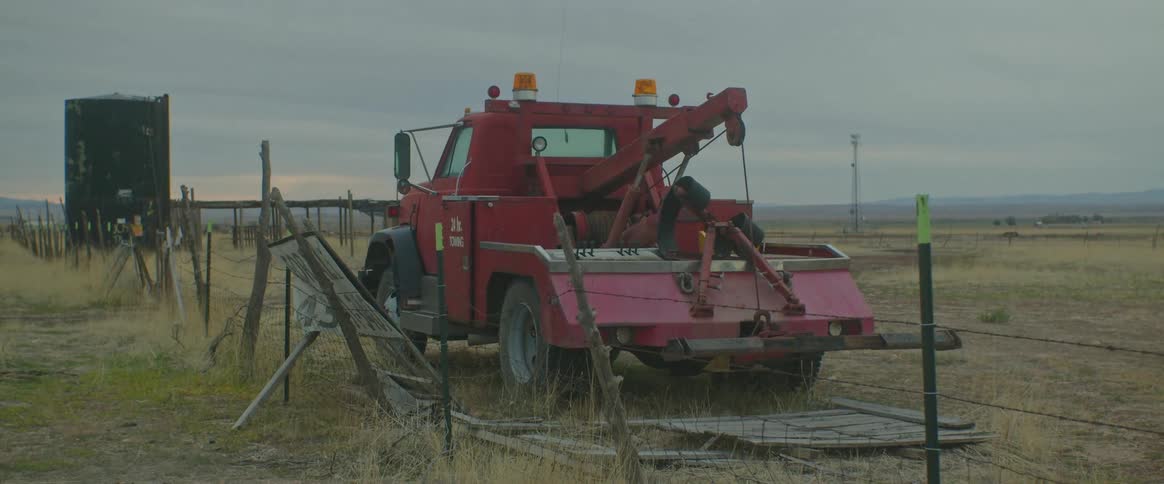 A small red tow truck parked on a lawn with fences