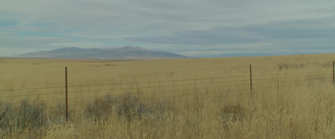View of a fence pasture and a mountain range on the horizon