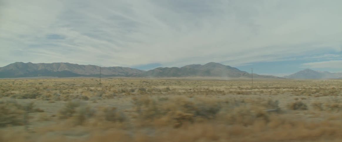 A pasture field in a rural landscape with mountains