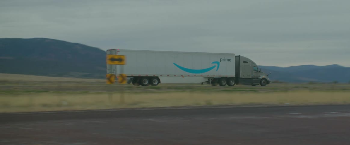 An amazon prime commercial truck drives down a highway in a remote area at dusk