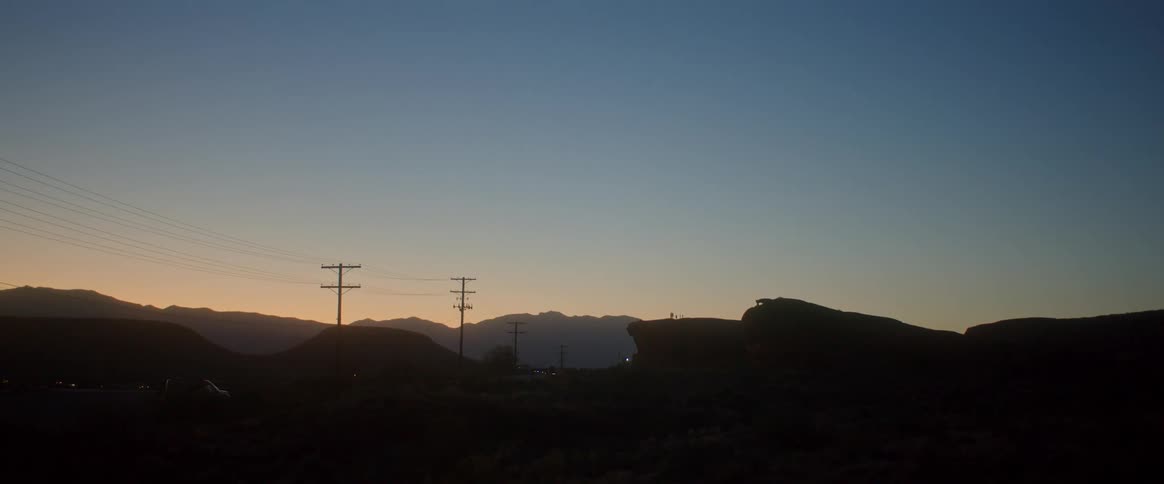 Silhouette of mountains against a dark orangetinged morning sky