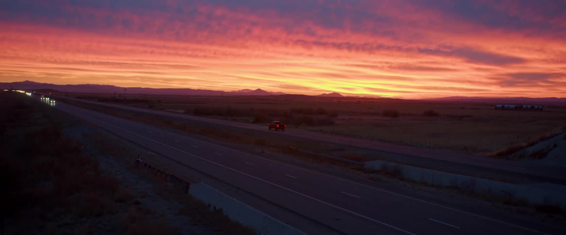 View of a highway with vehicles moving on a reddish dawn sky