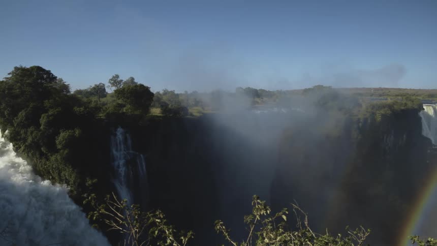 A vast waterfall pours over a wide cliff on clear sunny day