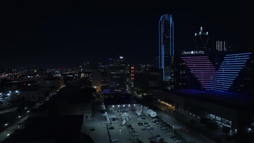 Orbiting aerial shot of metropolitan area at night time with many buildings covered in neon lights