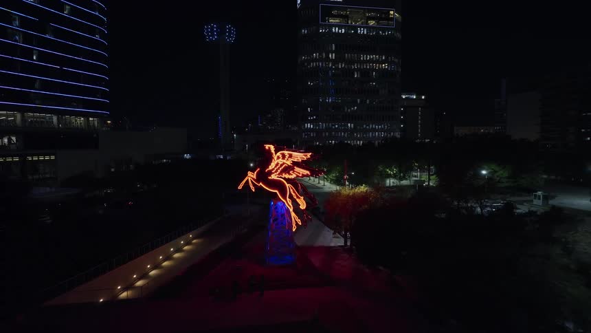 Neon light shaped like a winged horse in a city plaza