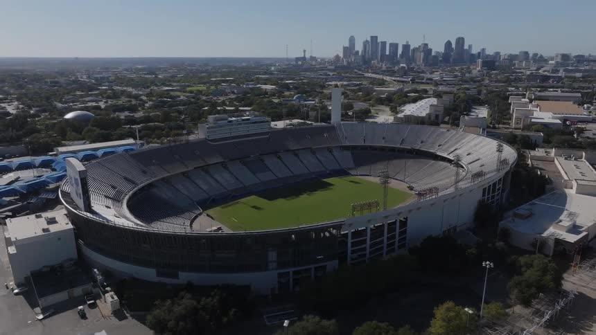 A huge sports arena with a lawn inside in a city with