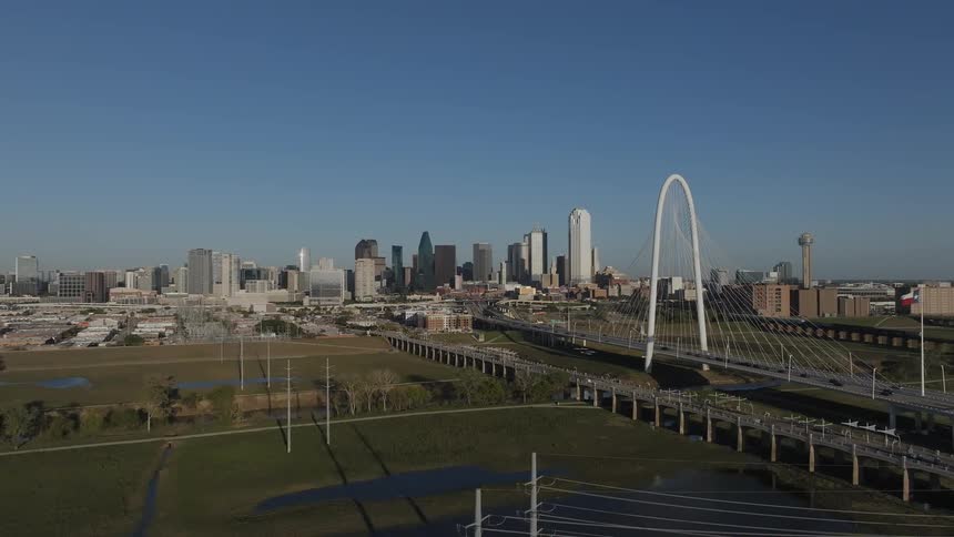 Aerial of traffic passing texas flag while crossing suspension bridge to and from downtown