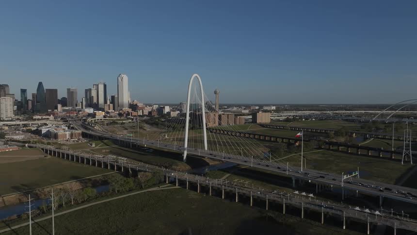 Panorama of a massive bridge over a river and a metropolis with skyscrapers on the horizon in daylight