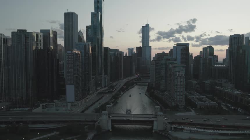 A metropolitan city with huge buildings and a small lake next to a busy highway with cars