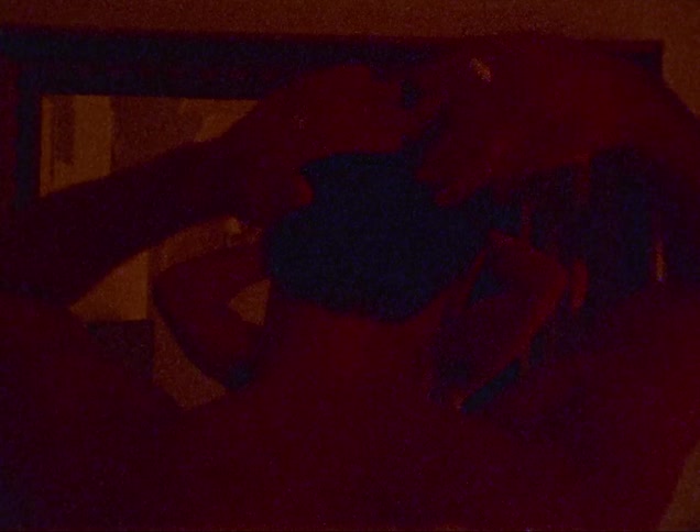 Man facing a mirror with his back and front visible while another man is combing his hair