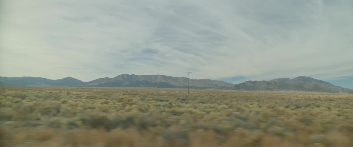 Plains next to the mountains seen from a moving vehicle