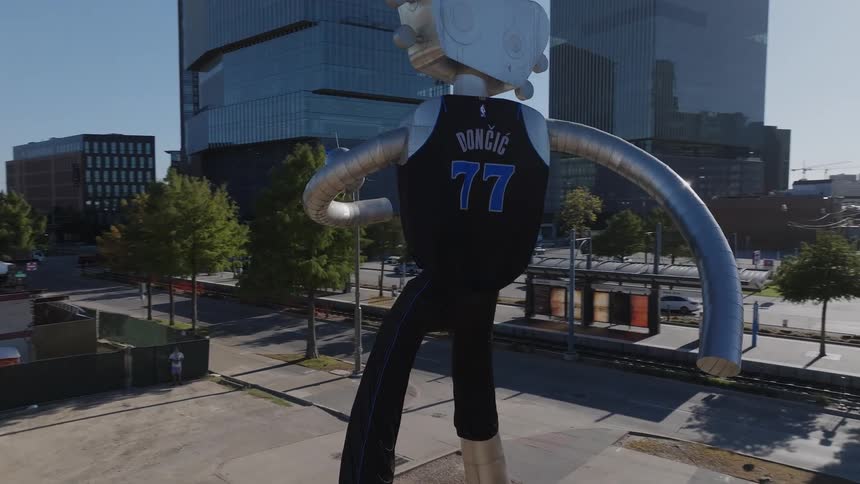 Statue with a jersey and a guitar shaped head towers over buildings a few blocks from downtown skyscrapers