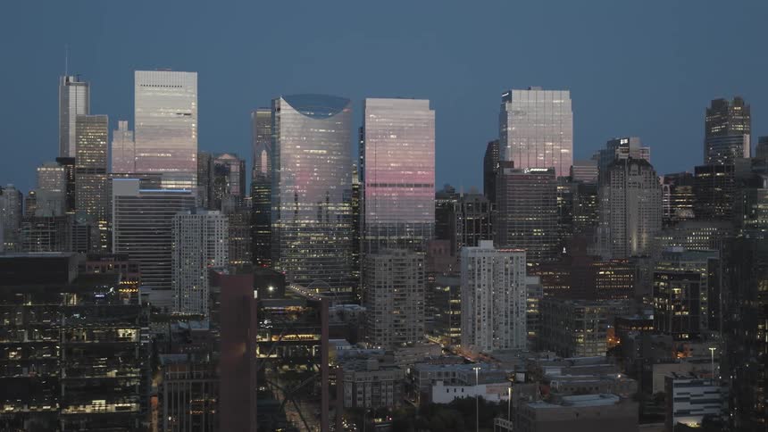 Aerial view of illuminated tall buildings in downtown area at dusk in the city