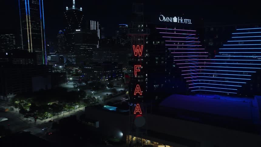 A tower with neon writing in a metropolitan city at night