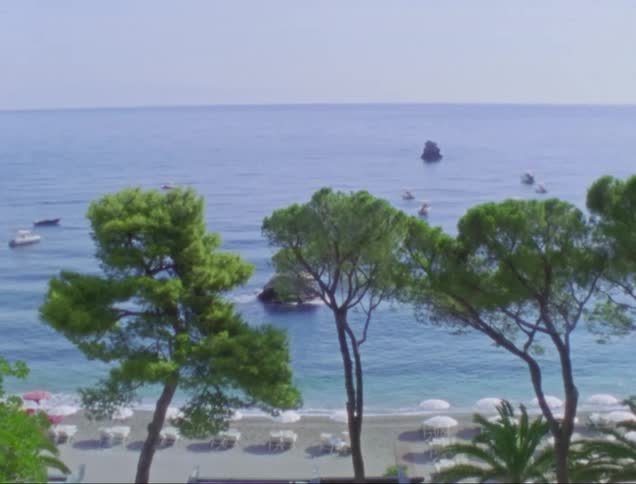 Boat floats near beach strewn with umbrellas and chairs