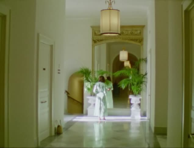 Lady in a robe looking in the mirror by the hallway during the day