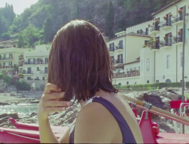 A woman is sitting on the beach by the resort