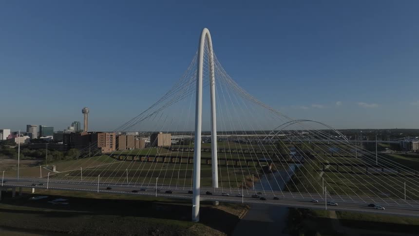 Vehicles drive across arched suspension bridge day blue sky
