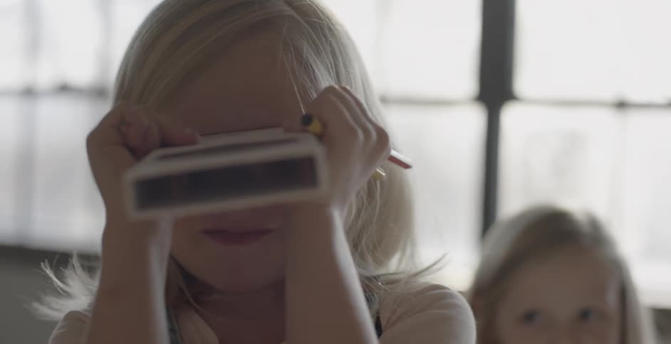 A little girl uses a box as binoculars