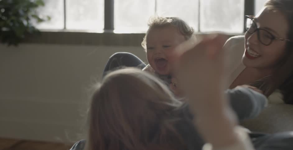 A woman kisses a baby and makes it laugh