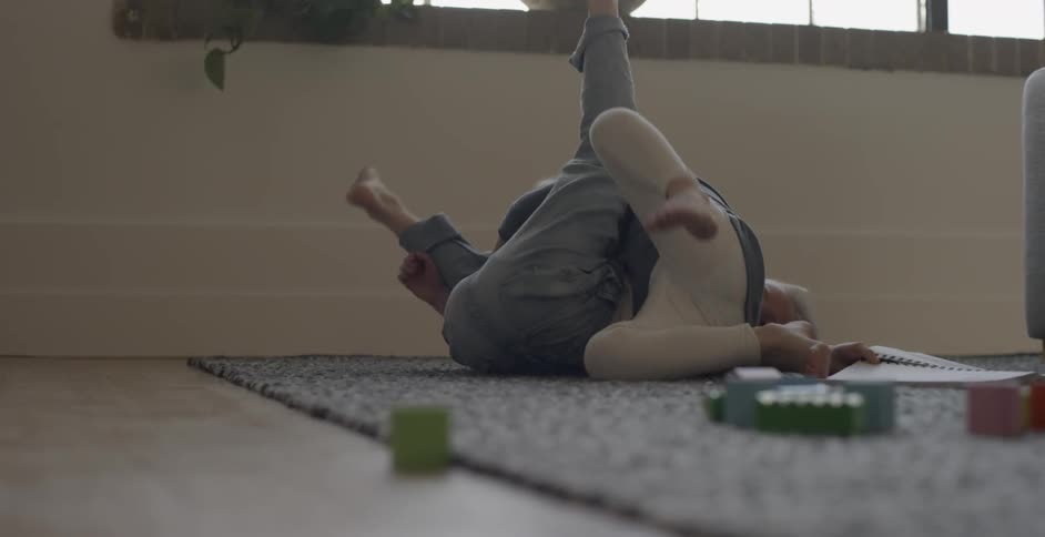 Two child are playing around on the carpet