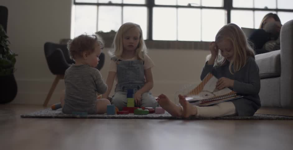 Three children play on a rug on the floor