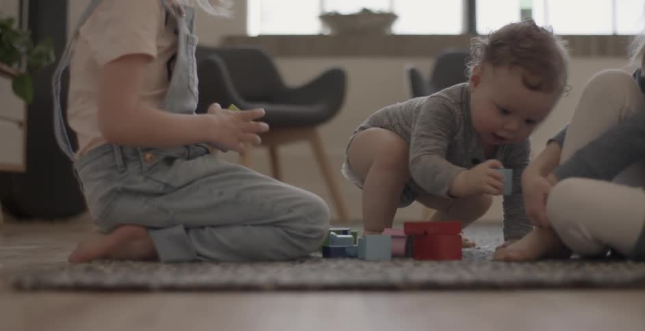 A baby and children play on the carpet