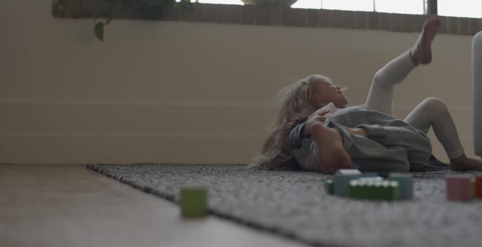 Two children wrestle on the carpet together