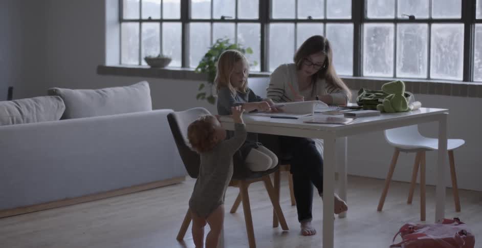 A woman and girl sit at a table and color