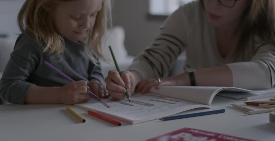 A woman and child both color in a book