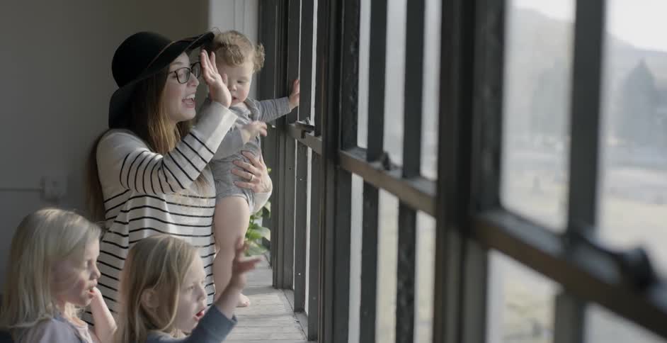 A woman and three children wave out of a window