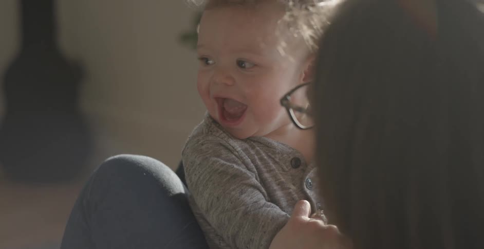 A baby is laughing in a mother's arms